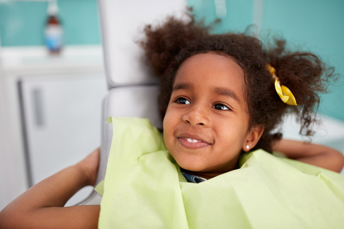 little girl smiling in dentist chair