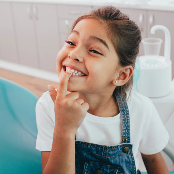 little girl pointing at her front teeth